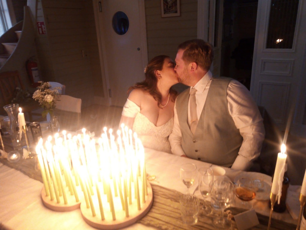 Hanna & Emil kysser varandra vid middagsbordet omringade av ljus